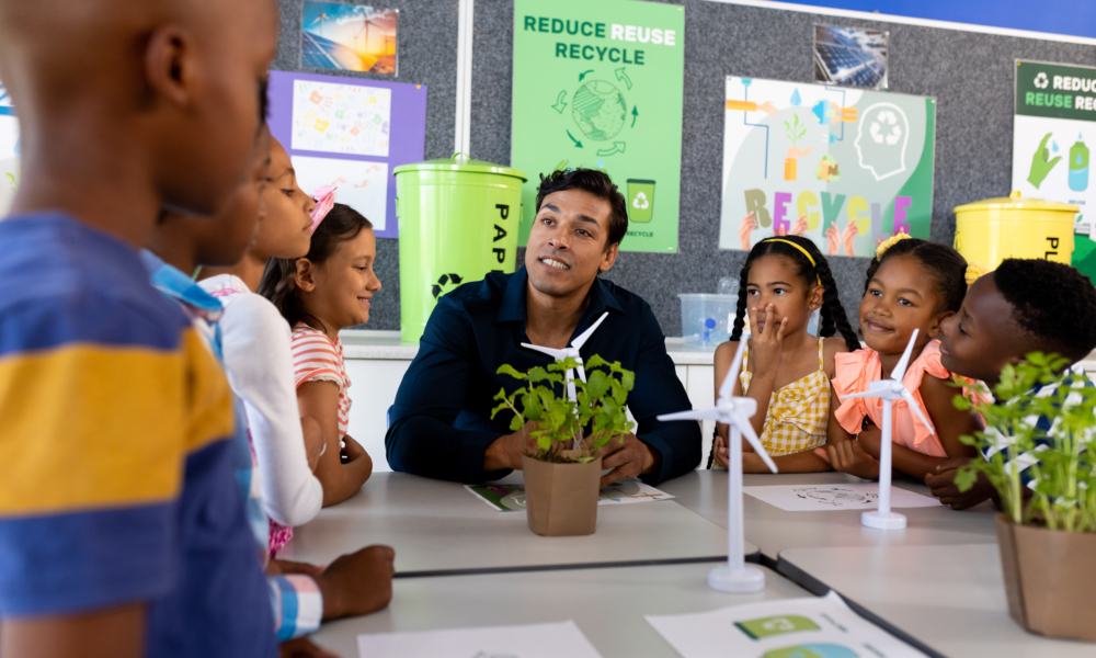 Teacher and children in classroom with miniature wind turbines and plants.
